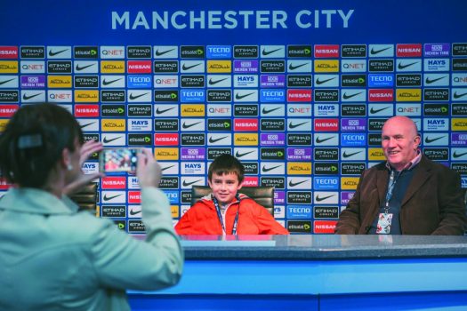 Manchester City Football - Photograph of supporter with sponsors logos in background